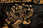 Wat Xieng Thong temple in Luang Prabang, Laos. Detail of the  intricate gold stencilling on black lacquer that decorate the walls of the sim. 